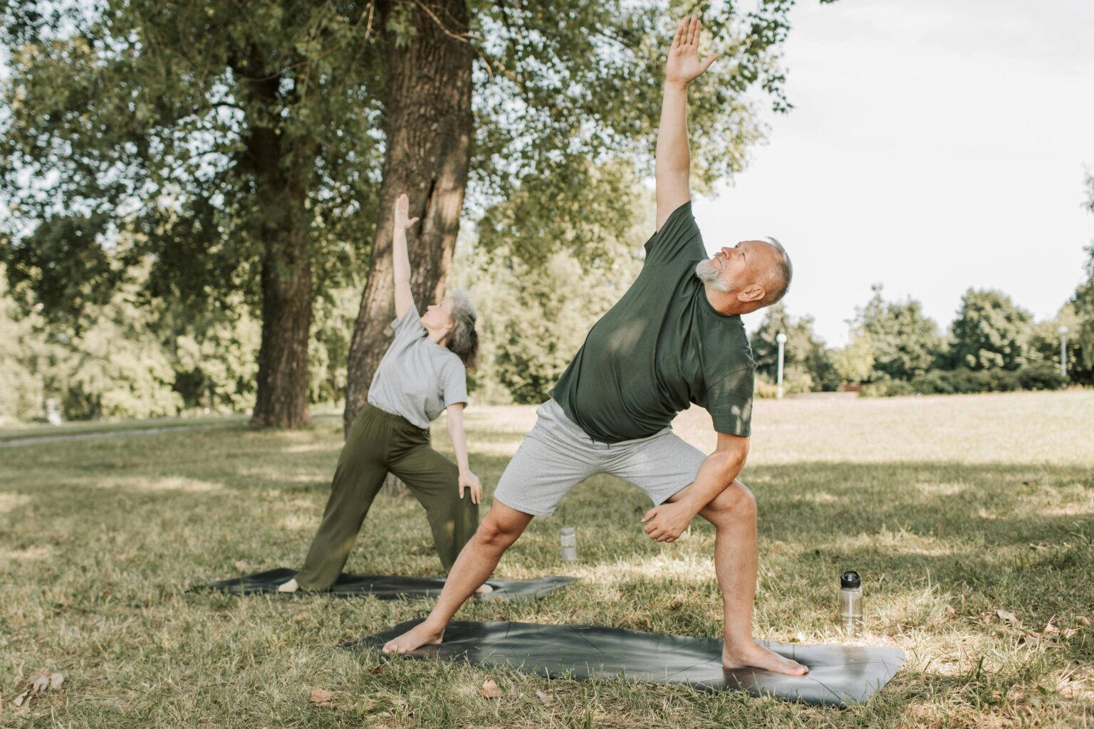 Un couple de seniors pratique le yoga dans un parc